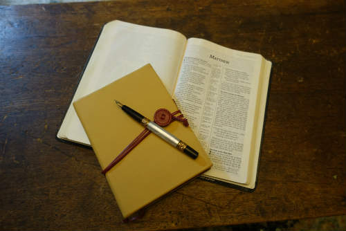 Image was here of a journal, a pen, and a Bible opened to the Book of Matthew.
