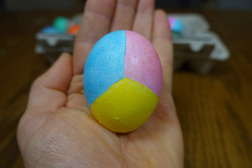 A single white chicken egg is seen, being held by a hand.  This image was displaying here.