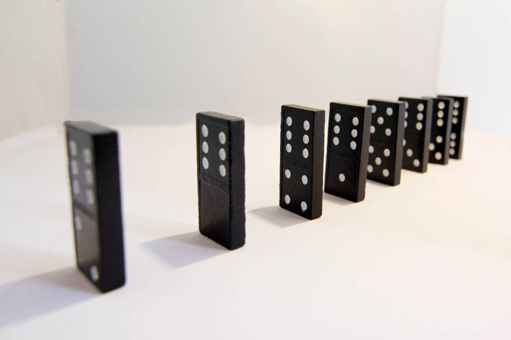 a line of dominos positioned to knock each other down, one after the other.