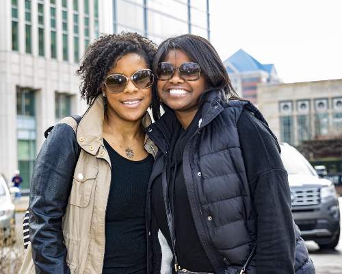 An image was here of two friends smiling an hugging each other from the side.