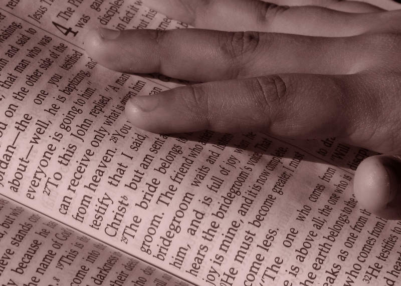 A hand is seen touching bible verses in an image that was displaying here.