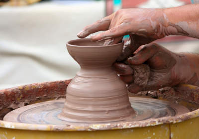 An image was here of a spinning wheel on which hands are shaping a pottery vase.