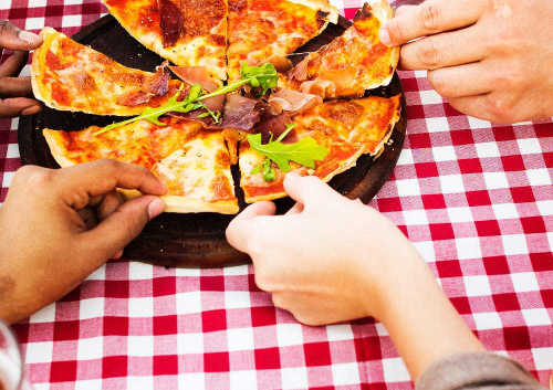 An image was here of hands reaching to share a pizza together.